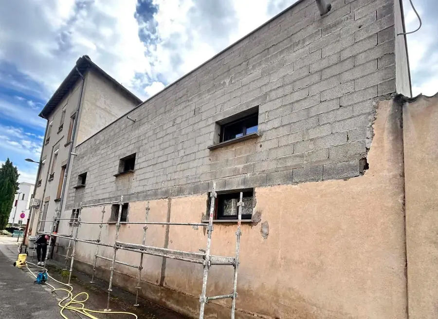 Mur pignon avant ravalement : enduit décollé et blocs apparents, échafaudage en place